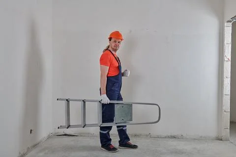 Angry engineer holding a stepladder under his arm Stock Photos