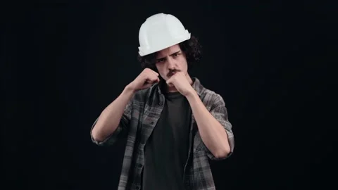 The angry engineer, with a white helmet, is ready to fight, he raises his fists Stock Footage 156277575