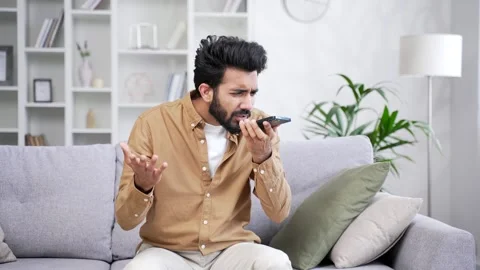 Angry excited young bearded man talking arguing over smartphone while sitting  Stock Footage 252205505