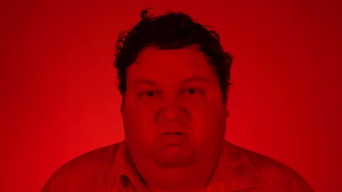 Angry grumpy young man frightened - feeling angry - red lighting Stock Footage 123166761