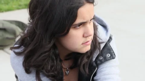 Angry looking non binary kid sitting on ground Stock Footage 155387021