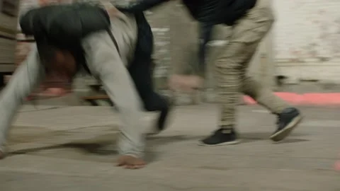 Angry man beats up another man wearing a black backpack, in front of a camper tr Stock Footage 199460445