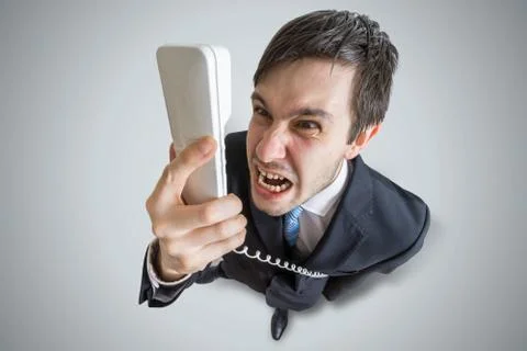 Angry man is calling and shouting to the telephone. View from above. Stock Photos