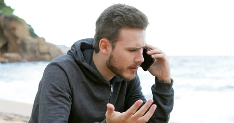 Angry man calling on phone on the beach Vidéo 98299313