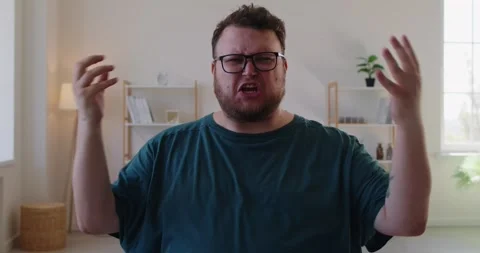 Angry man clenching fist while arguing during online call in home office Stock Footage 319029651
