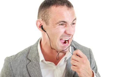 Angry man with earbuds connected on mobile phone yelling Stock Photos