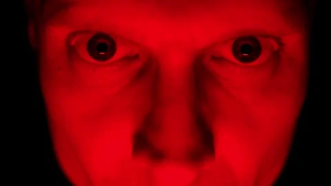 Angry man face under red lighting, showing intense emotions of rage and Video stock 295928411