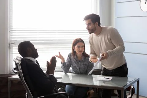 Angry man pointing an error in document to employee. Stock Photos