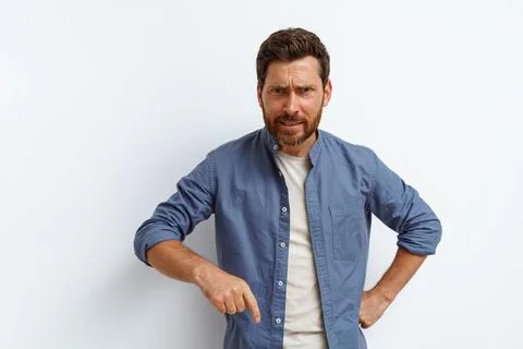 Angry man points finger down and say to you come here right now while standing Stock Photos