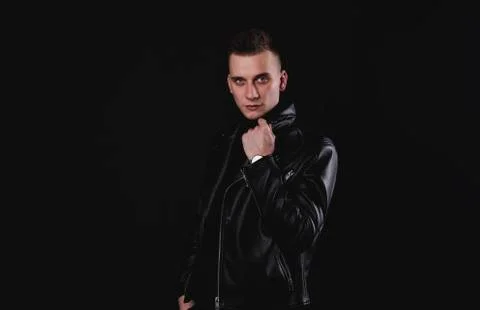 Angry man pulling his leather jacket's collar on black studio background Foto stock