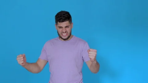 Angry man screaming and shouting on blue background wearing t shirt Stock Footage 123944892