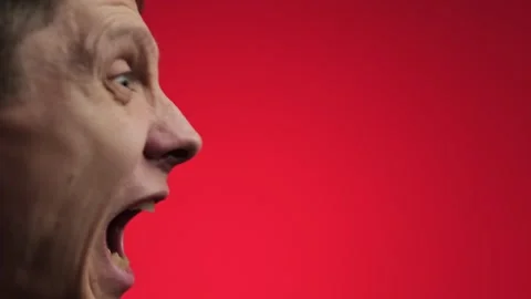 Angry man shouting intensely against a red background. Stock Footage 297748248