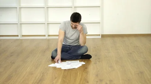 The angry man sit on the floor and hold the receipt. Real time capture Stock Footage 70025516
