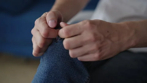 Angry man struggling with ill-fitting denim jeans, ripping fabric around knee Stock Footage 318019273