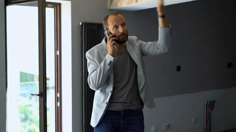 Angry man talking on cellphone standing at new home Stock Footage 97155433