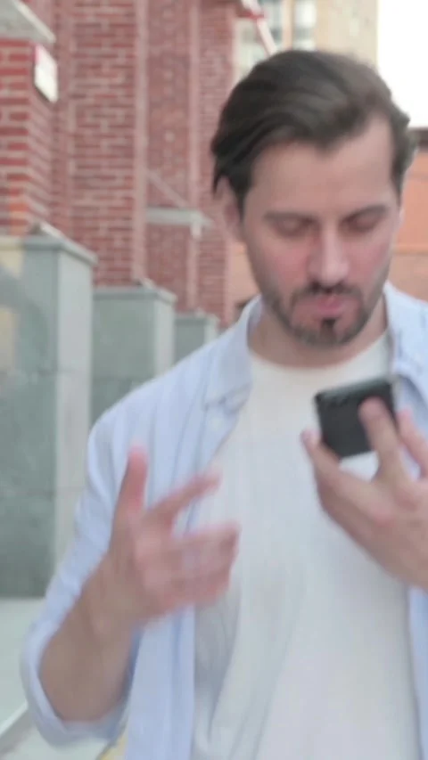 Angry Man Talking on Phone Angrily while Walking in Street, Vertical Video Stock Footage 339664637