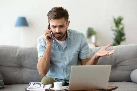Angry man talking on phone disputing over computer laptop problem 스톡 사진