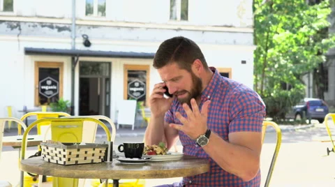 Angry man talking by smartphone during breakfast in cafe Vidéo 67627287