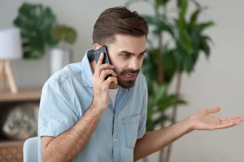 Angry man talking on smartphone solving work problem Stock Photos