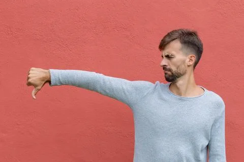 Angry man with thumb down on red wall background Stock Photos