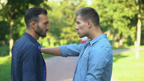 Angry men pushing and threatening each other outdoors solving problem with force Video stock 115313860