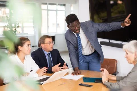 Angry middle-aged man shouting at his business partners sitting around table Stock Photos