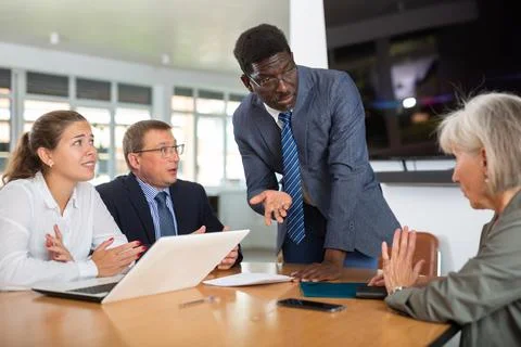 Angry middle-aged man shouting at his business partners sitting around table Stock Photos