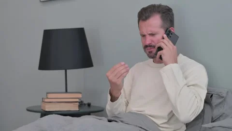 Angry Middle Aged Man Talking on Phone while in Bed Stock Footage 287898956