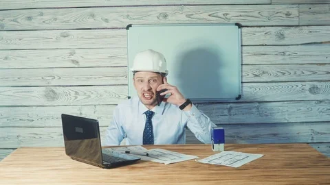 An angry nervous architect working on drawings of new projects and talking on Видео 104238481