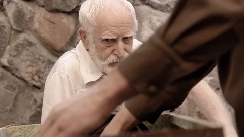 Angry NKVD soldier interrogates a miserable, bearded, gray-haired old man on the Stock Footage 100372567