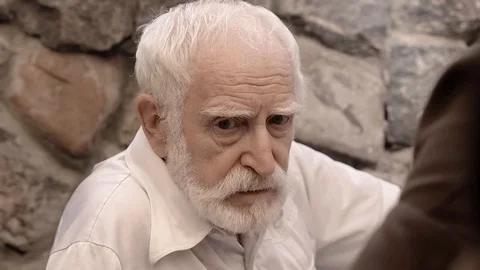 Angry NKVD soldier interrogates a miserable, bearded, gray-haired old man on the Stock Footage 100372579