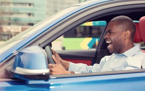 Angry pissed off aggressive young man driving car shouting Stock Photos