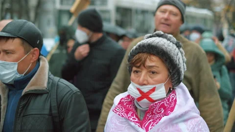 Angry russian activist marching in red cross mask with flags and protest placard Stock Footage 154452652