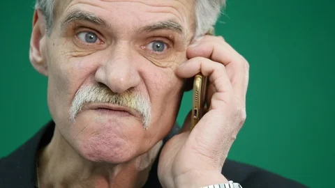 Angry senior man speaking on mobile phone on grren background Stock Footage 86407610