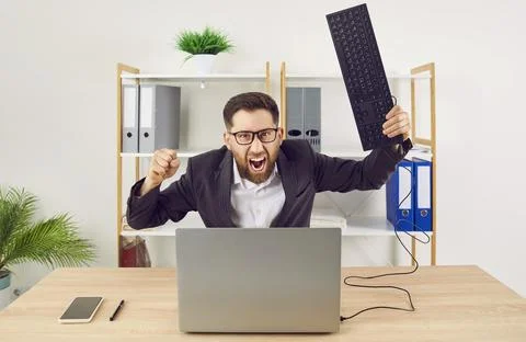 Angry shouting man working on workplace in office trying to destroy the monitor Foto stock