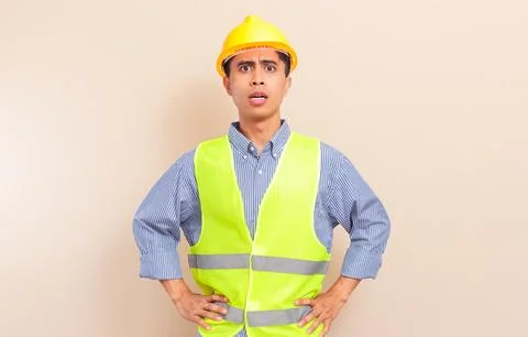 Angry Southeast Asian construction worker in yellow hard hat and safety ves.. Stock Photos