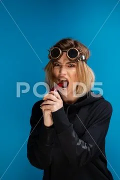 Angry steam punk girl with glasses biting a dark red chilli pepper with attitude Stock Photos