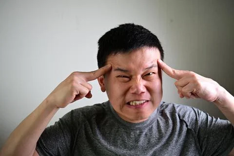 Angry stressed man pointing at temples showing mental pressure frustration 写真素材