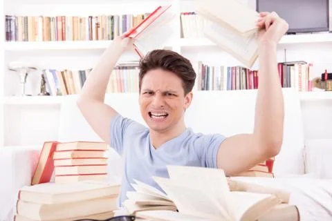 Angry student  surrounded by books  throws books Stock Photos