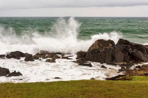Angry waves crash over rocks on the coast during a summer storm Stock Photos