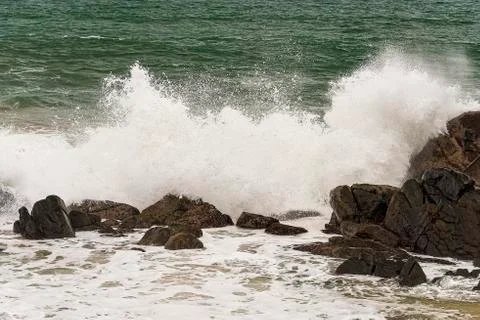 Angry waves crash over rocks on the coast during a summer storm Stock Photos