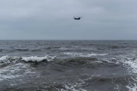 Angry waves in the ocean with strong currents, moody sky and helicopter Stock Photos