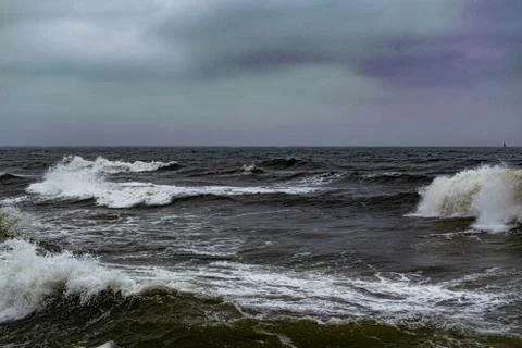 Angry waves in the ocean with strong currents and a moody sky. Beach and sea Stock Photos