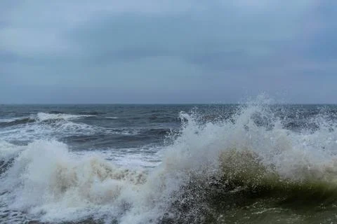 Angry waves in the ocean with strong currents and a moody sky. Beach and sea Stock Photos