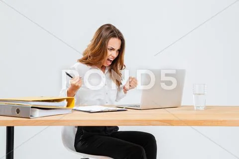 Angry young businesswoman using laptop and shouting Stock Photos