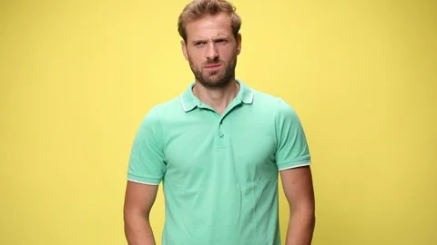Angry young casual man making a face, holding hands to mouth and screaming on Stock Footage 137449044