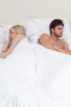 Angry young couple avoiding each other in bed Stock Photos