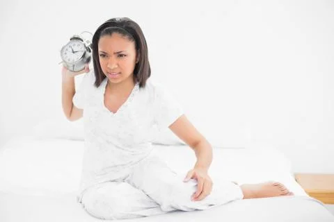 Angry young dark haired model throwing an alarm clock Stock Photos