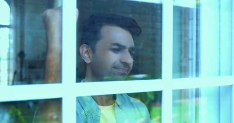 Angry young Indian man hitting glass window, showing frustration in modern home Stock-Footage 342692935