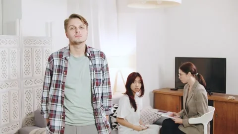 Angry young man appears tense in the foreground while two women engage in a Stock Footage 320439928